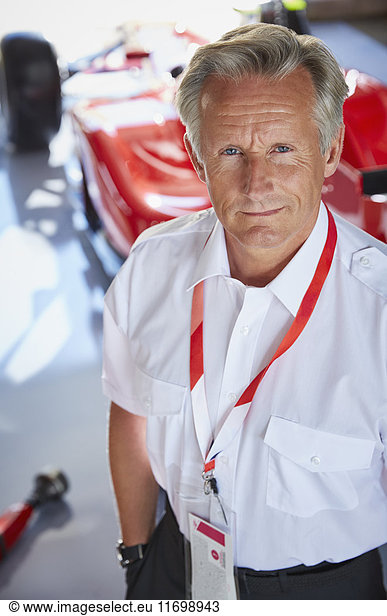 Portrait confident formula one racing manager in repair garage