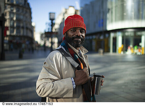 Portrait confident handsome businessman in stocking cap on city street