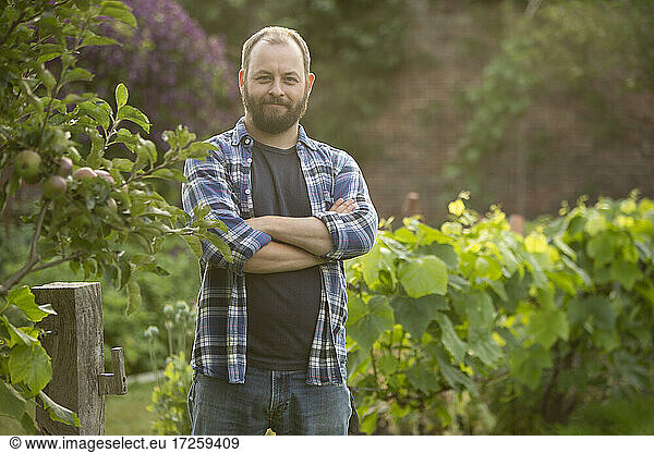 Portrait confident handsome man with beard in garden