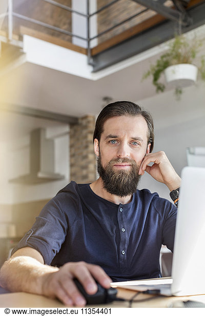 Portrait confident male design professional working at laptop in office