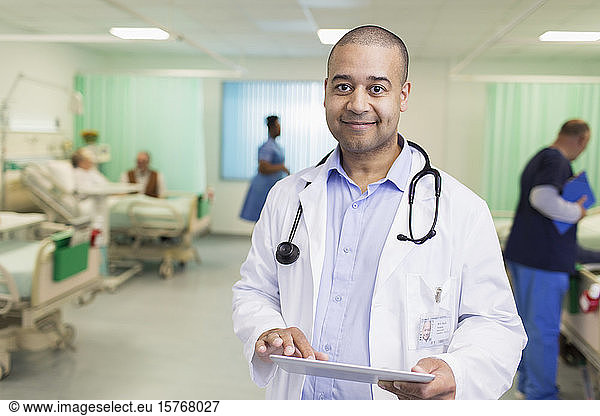 Portrait confident male doctor making rounds  using digital tablet in hospital ward