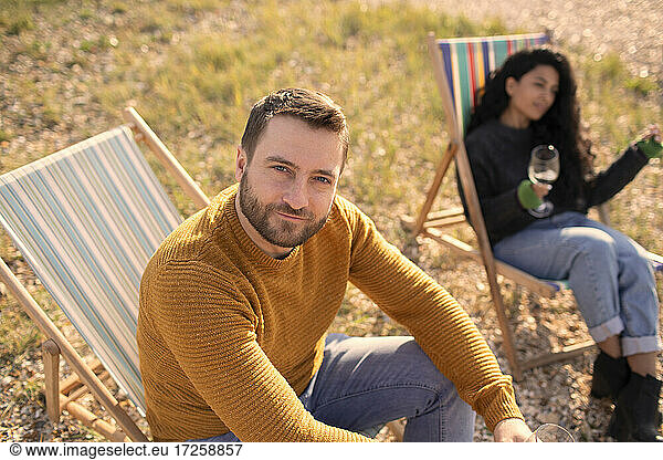 Portrait confident man relaxing in lawn chair by girlfriend