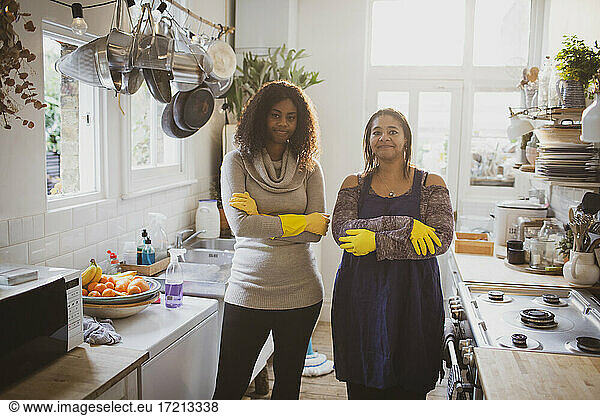 Portrait confident mother and daughter cleaning kitchen