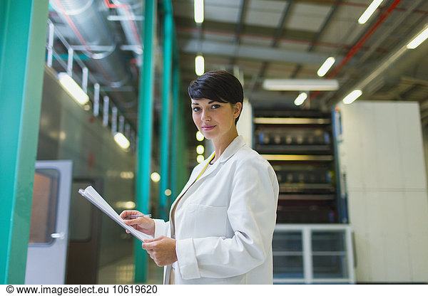 Portrait confident scientist with paperwork in factory