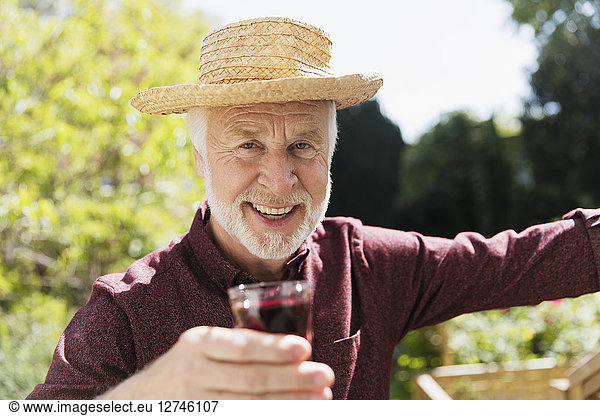 Portrait confident senior man drinking red wine in garden