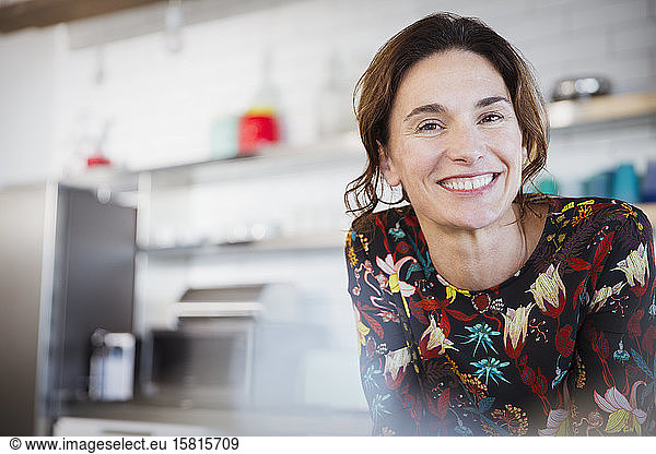 Portrait confident smiling brunette woman in kitchen