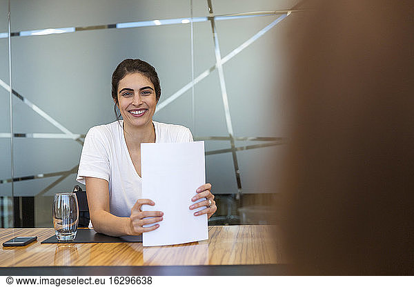 Portrait confident smiling businesswoman with paperwork in meeting