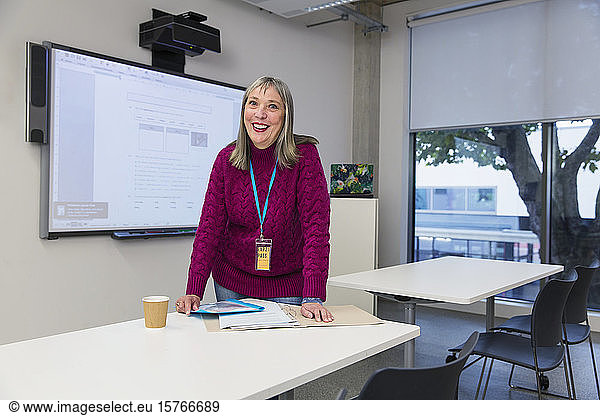 Portrait confident  smiling community college instructor preparing in classroom