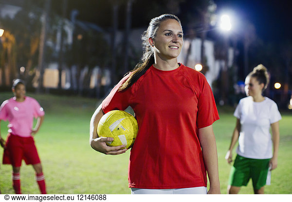 Portrait confident  smiling young female soccer player on field at night