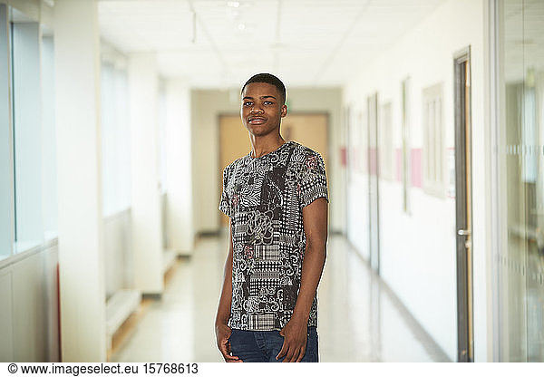 Portrait confident teenage boy in high school corridor