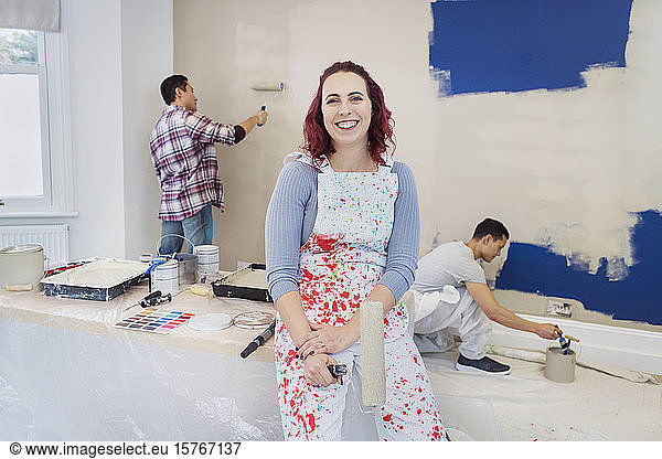Portrait confident woman in overalls painting room with friends