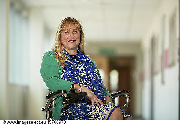 Portrait confident woman in wheelchair in corridor