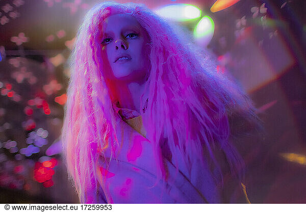 Portrait confident woman with pink hair in nightclub