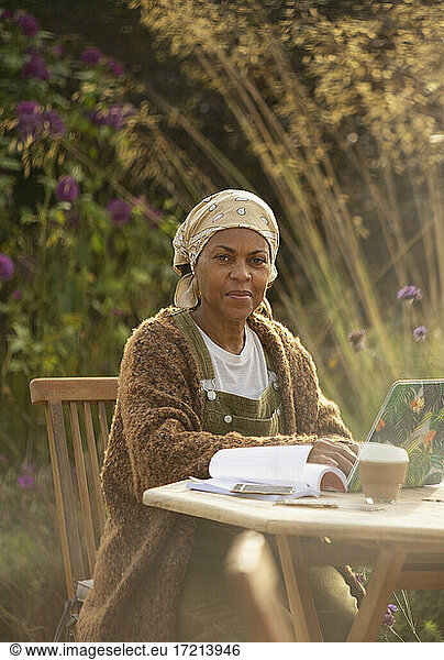 Portrait confident woman working at laptop on garden patio table