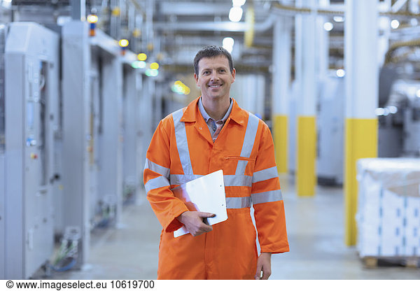 Portrait confident worker in reflective clothing with clipboard in factory