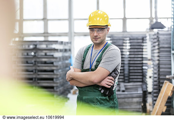 Portrait confident worker with arms crossed in factory