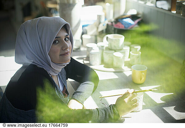Portrait confident young female Muslim artist in art studio