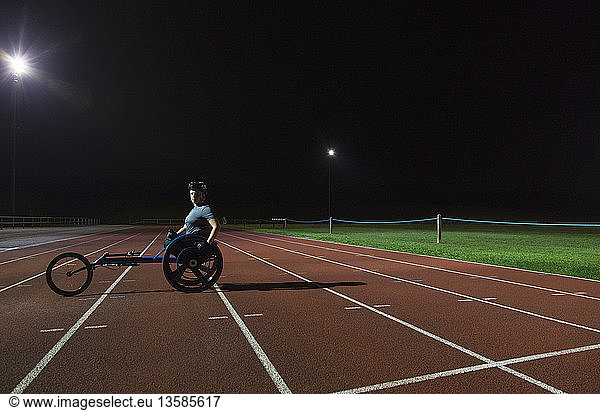 Portrait confident young female paraplegic athlete training for wheelchair race on sports track