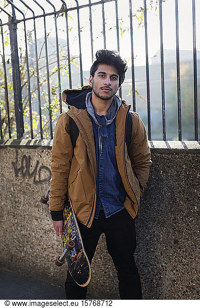 Portrait confident young man holding skateboard