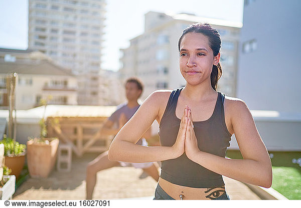 Portrait confident young woman practicing yoga on sunny rooftop