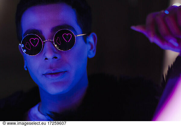 Portrait cool young man in sunglasses with heart reflection in dark