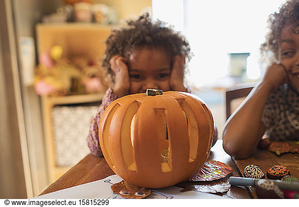Portrait cute girl carving Halloween pumpkin at table