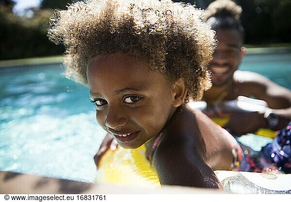 Portrait cute girl with curly hair in sunny summer swimming pool