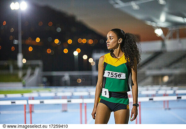 Portrait determined track and field athlete on track at night