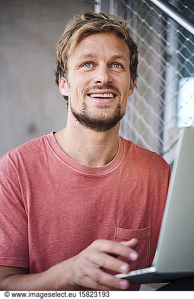 Portrait eines jungen Mannes mit T-Shirt und Laptop