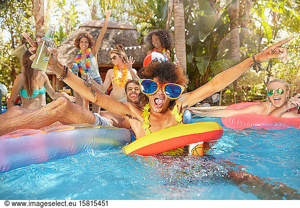 Portrait exuberant young friends drinking and playing in summer swimming pool