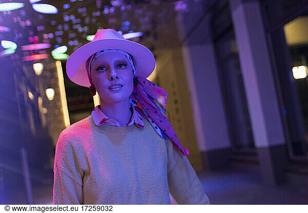 Portrait fashionable woman in fedora under neon lights