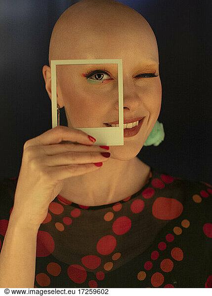 Portrait fashionable woman with shaved head and polaroid cut out