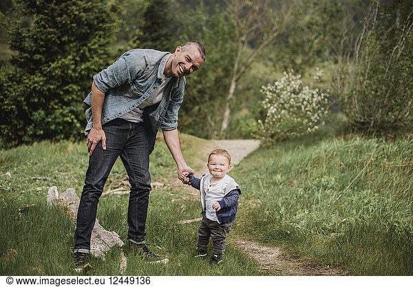 Portrait father and baby son walking on grassy path