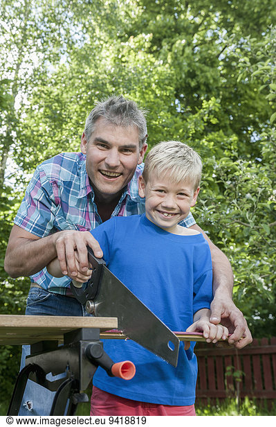Portrait father son sawing wood building