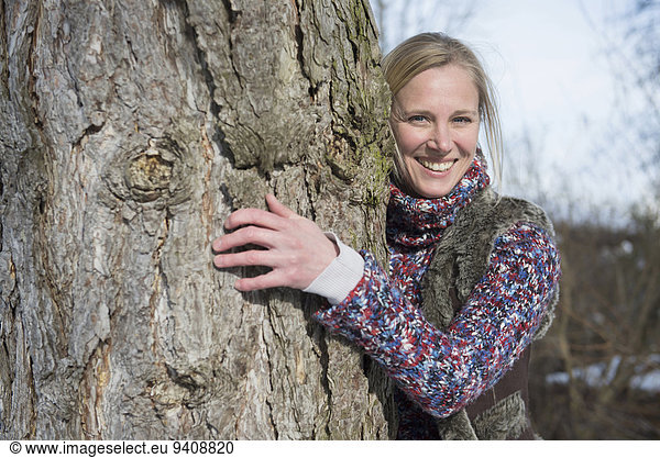 Portrait Frau umarmen lächeln Baum Baumstamm Stamm
