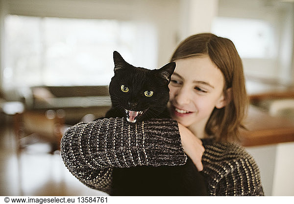 Portrait girl holding hissing black cat
