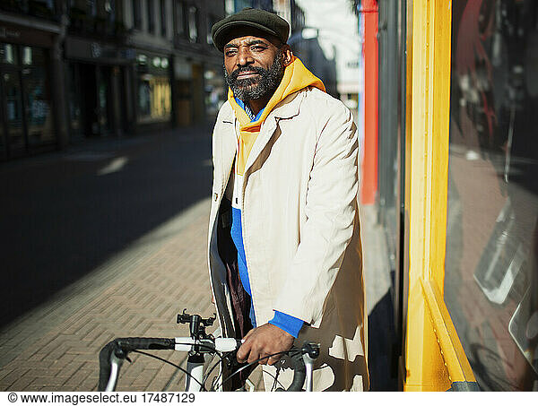 Portrait handsome man with. bicycle at sunny city storefront