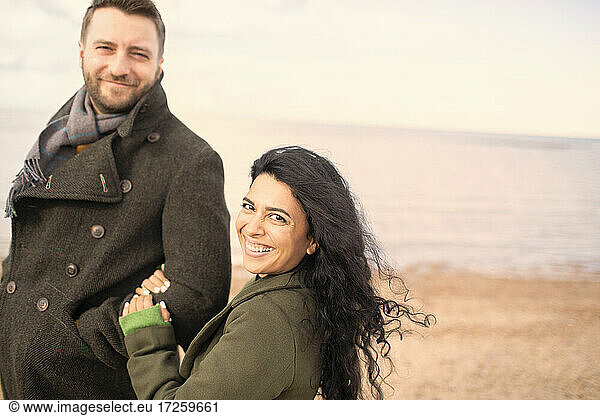 Portrait happy carefree couple on winter ocean beach