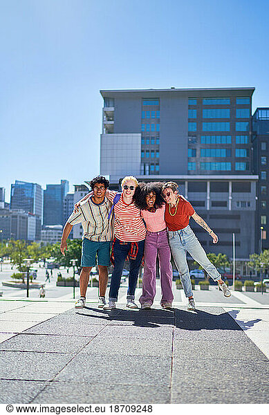Portrait happy  carefree friends hugging in sunny city