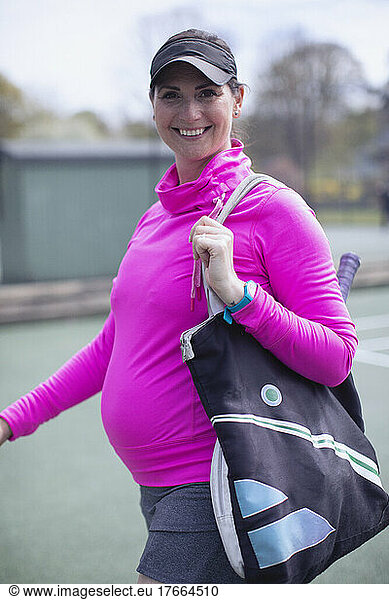 Portrait happy confident pregnant woman on tennis court