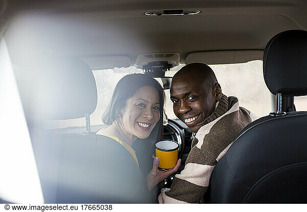 Portrait happy couple drinking coffee inside car
