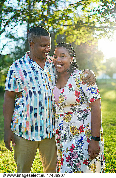 Portrait happy couple hugging in sunny summer park