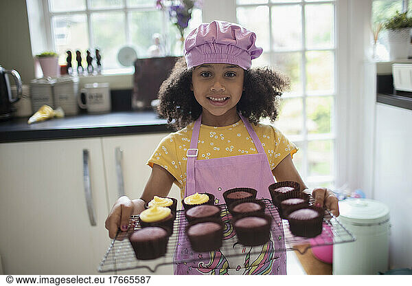 Portrait happy cute girl baking cupcakes on rack