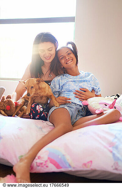 Portrait happy disabled daughter with mother and dog on bed