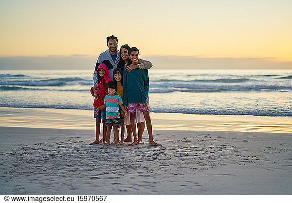 Portrait happy family on ocean beach at sunset