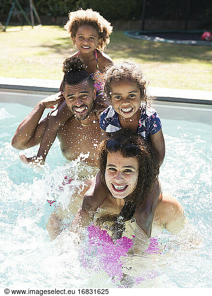 Portrait happy family splashing in sunny summer swimming pool