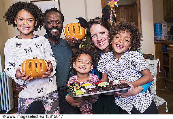 Portrait happy family with carved pumpkins and Halloween cupcakes