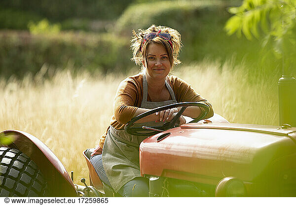 Portrait happy female farmer driving tractor