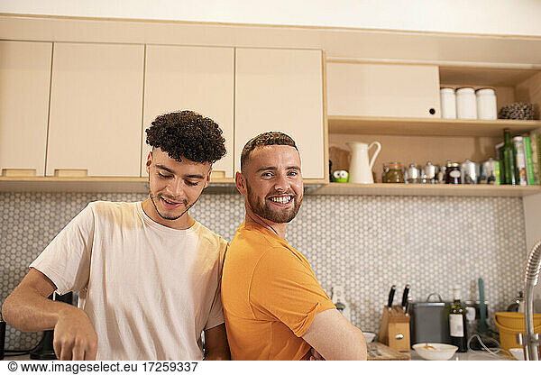 Portrait happy gay male couple in kitchen