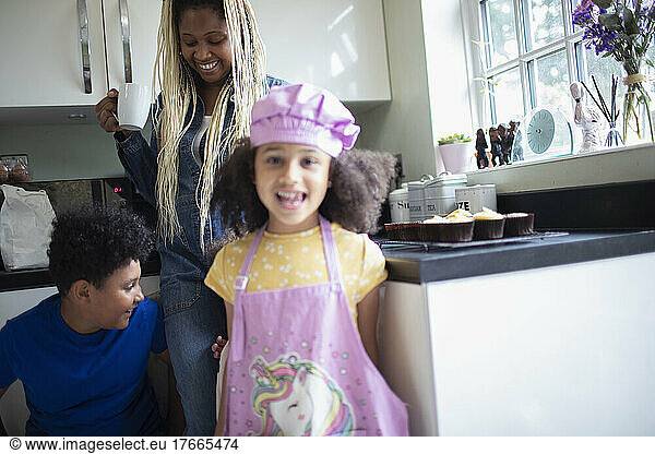 Portrait happy girl in unicorn apron in kitchen with family